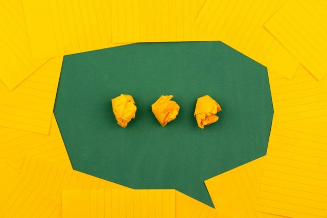 A paper in the shape of a speech bubble with crumpled paper dots on top of it