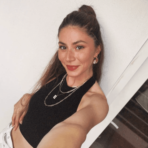 Woman in a black dress posing indoors.