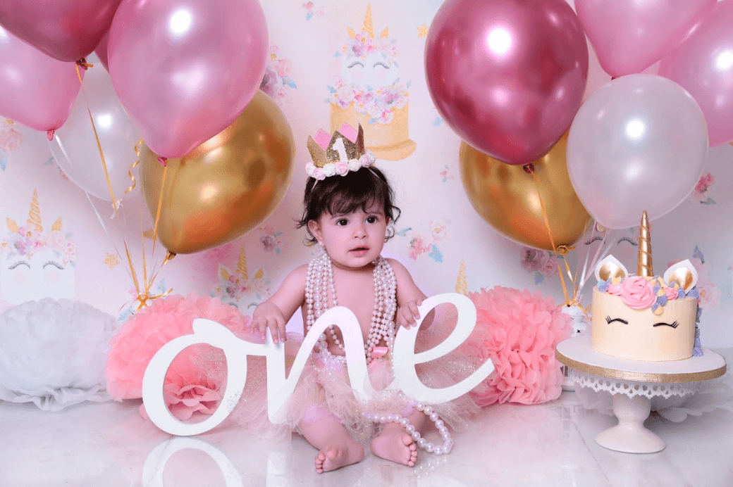 Baby girl having a first birthday cake smash photoshoot with a pink theme.