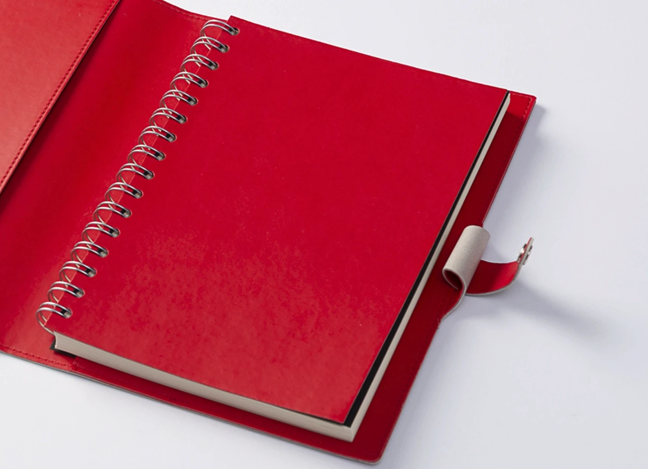 Open notebook showing red spiral binding and closure strap.