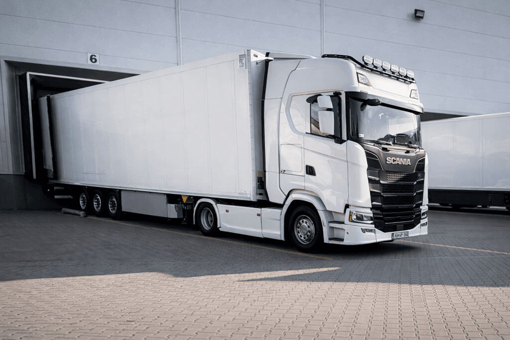 Hűtős áruszállítási, fuvarozási hűtős nyerges kamion áll egy logisztikai központ rakodójában