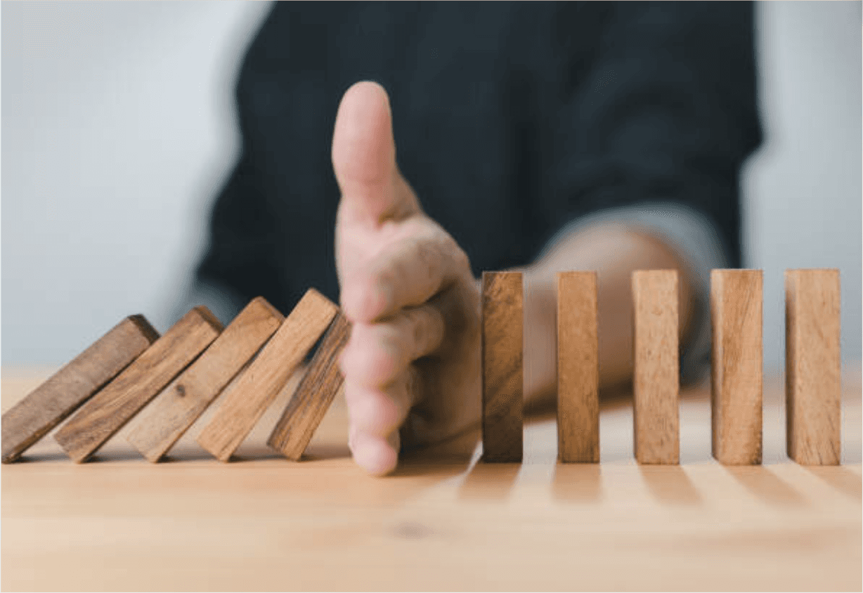 A hand blocking a set of dominos from all falling down. This represents the idea of prevention