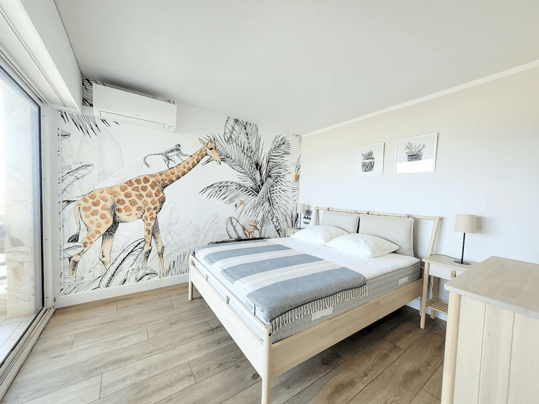 Modern open-concept living room with a large beige sectional, a wall-mounted TV, sleek barstools, wooden accents, and natural light from large windows. Cozy atmosphere.