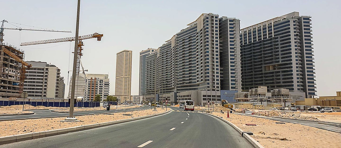 Modern high-rise architecture and paved roads in the developing Dubailand Residence Complex community.