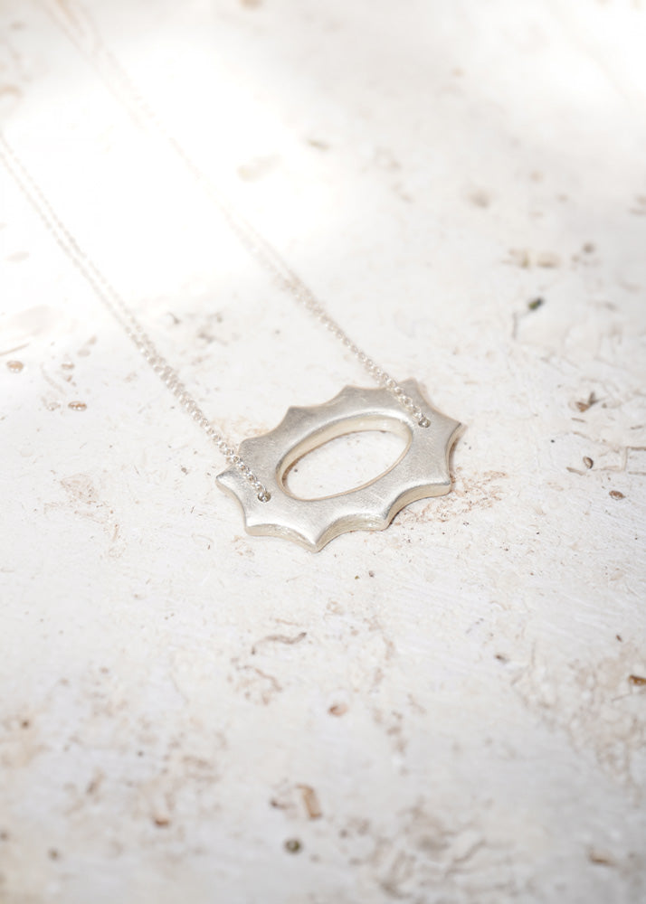 Silver necklace with a unique pendant on a light marble surface