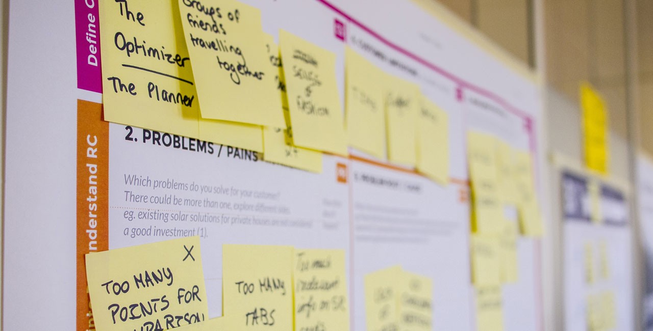 Designer reviewing UX wireframes and site architecture sketches on a large whiteboard