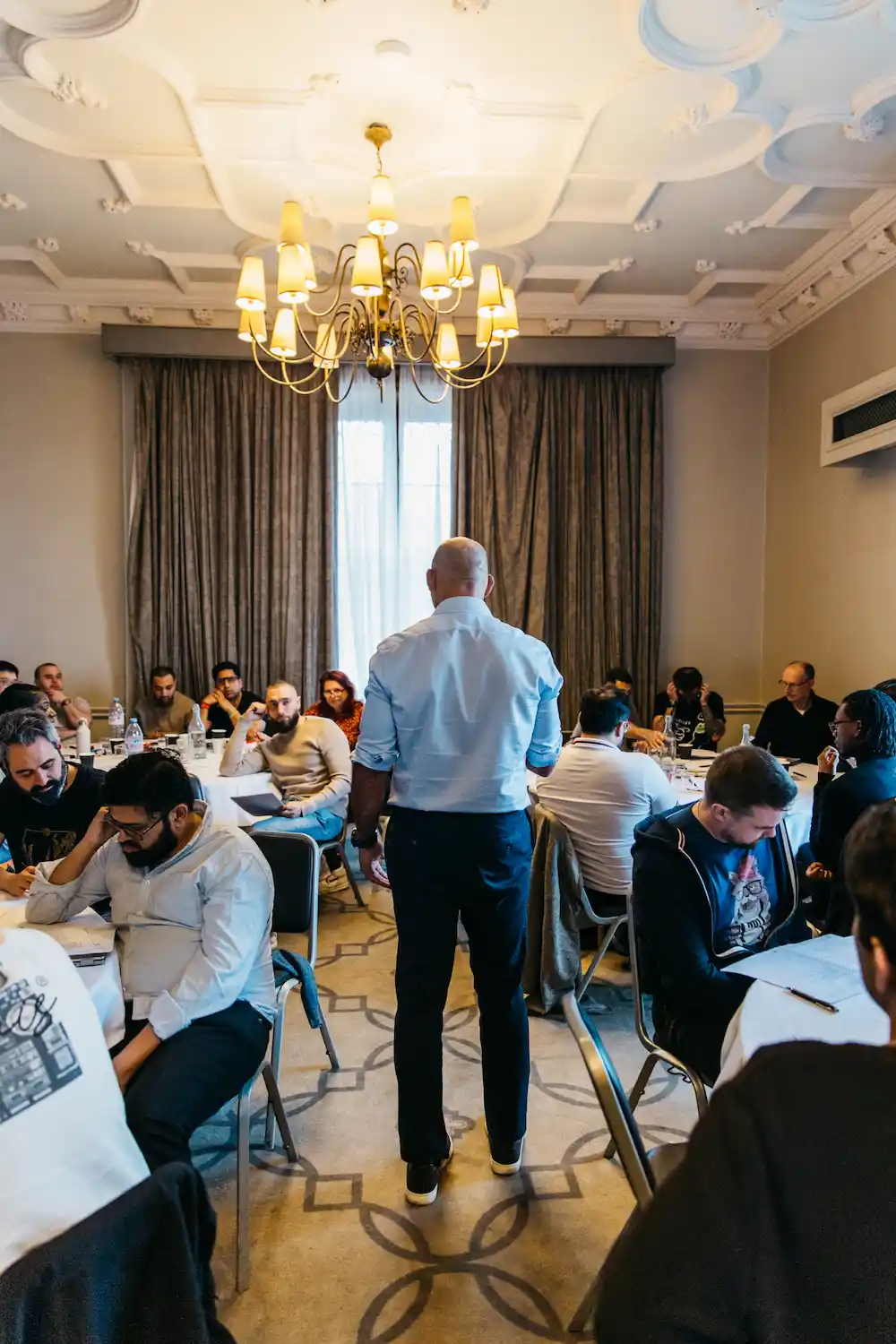 People sitting in a room with tables and chairs.