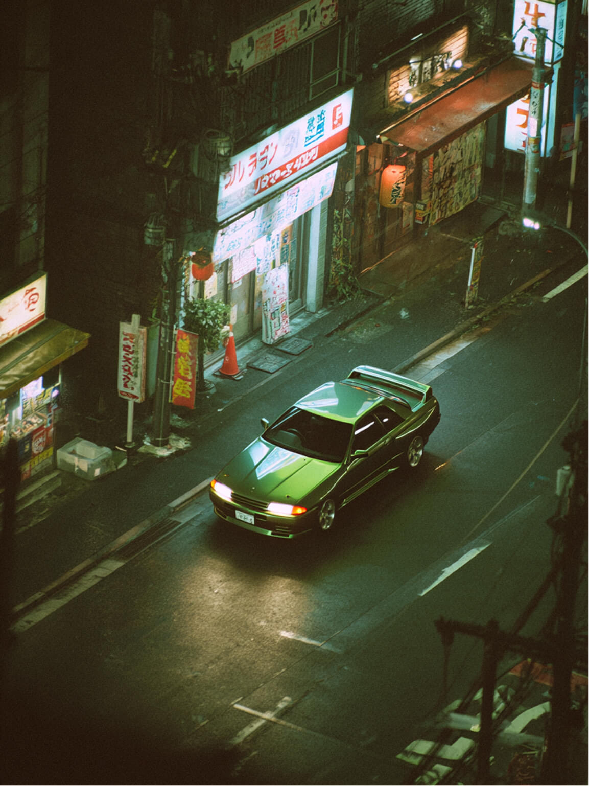 Green car under neon lights in a rainy city street