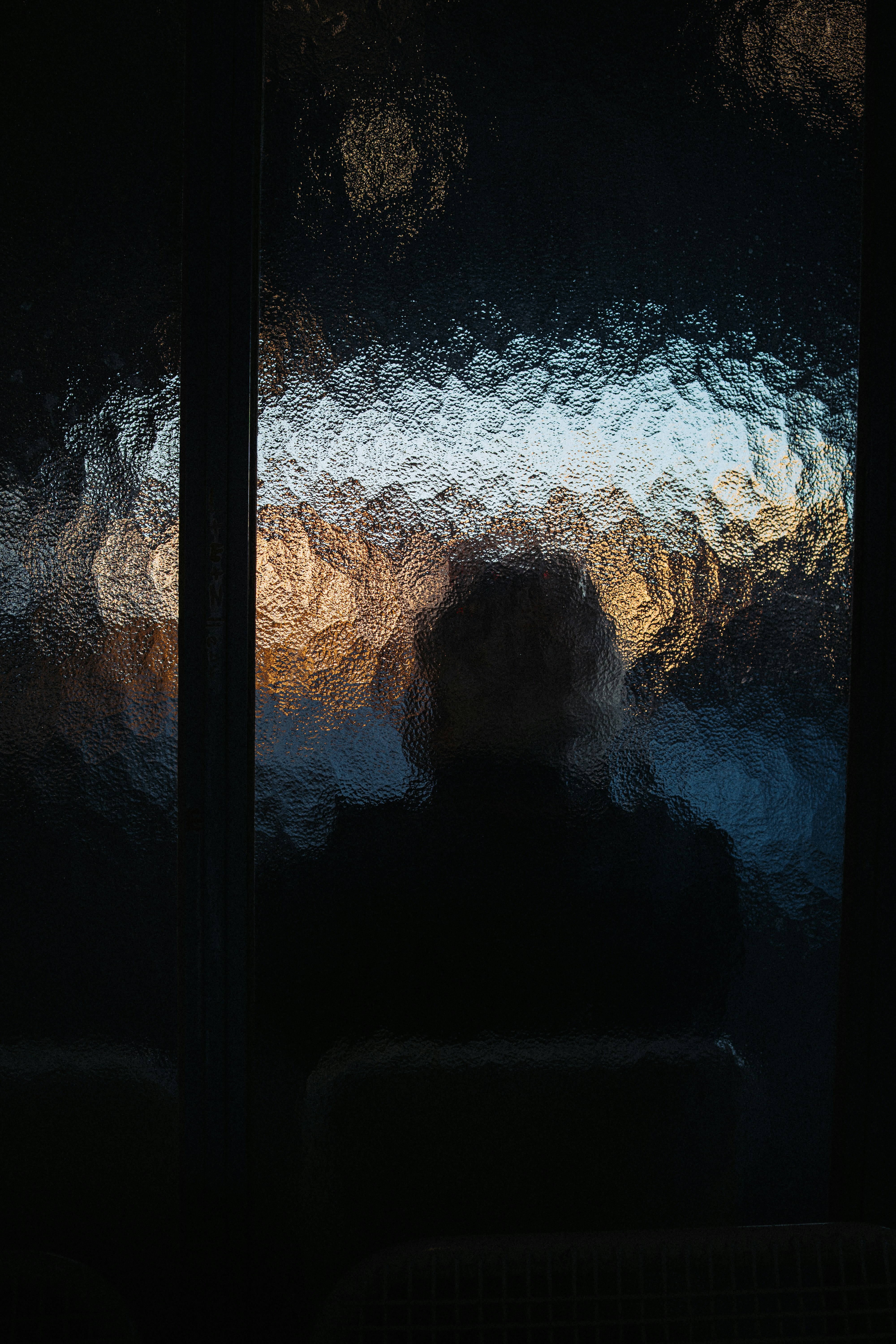 Silhouette of a person seen through textured glass