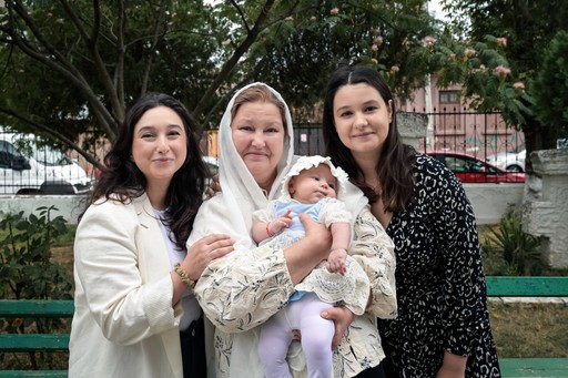 Nașele ținând bebelușul în brațe după botez.