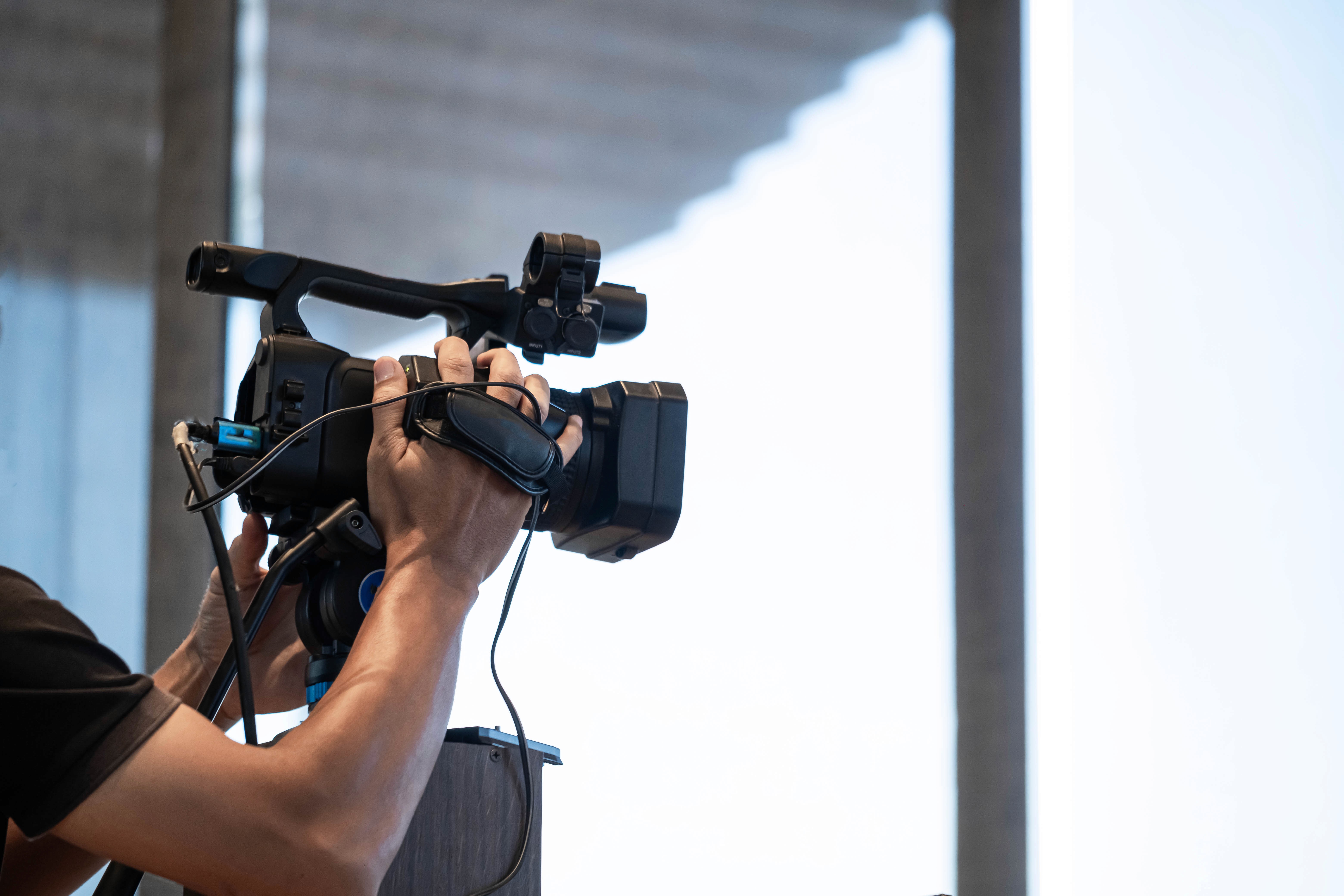 Camera operator filming with a professional video camera setup, representing expert video production services in Noida.