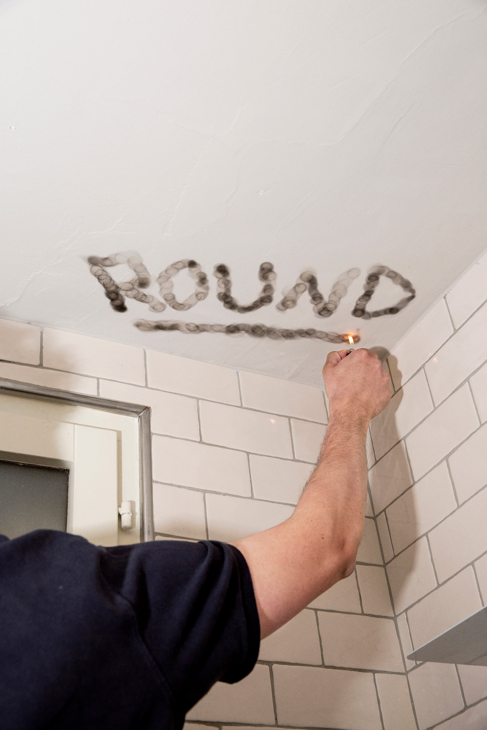 A man burning letters onto a ceiling with a lighter