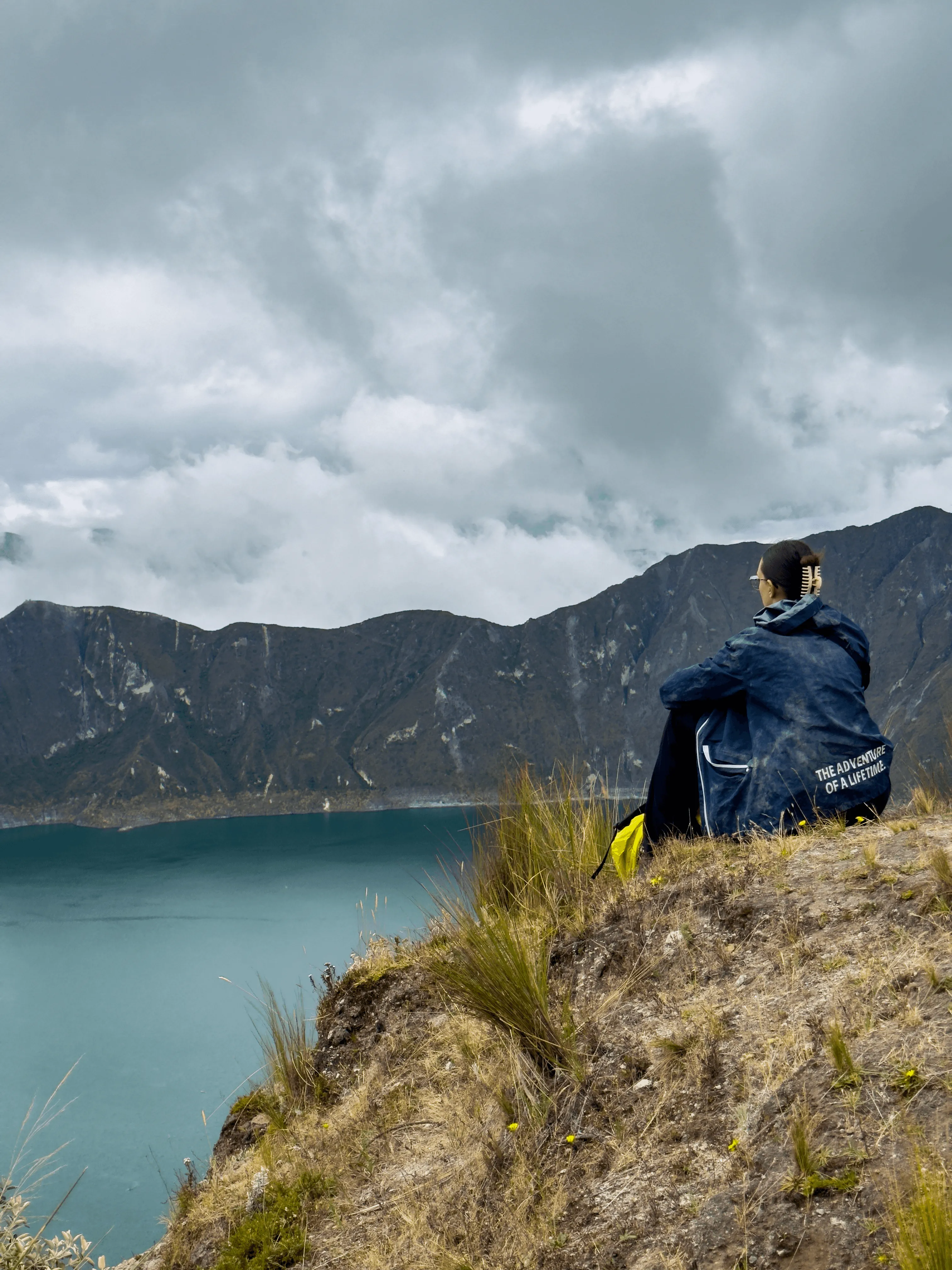 Personne assise au bord d'un ravin en face du lac de Quilotoa