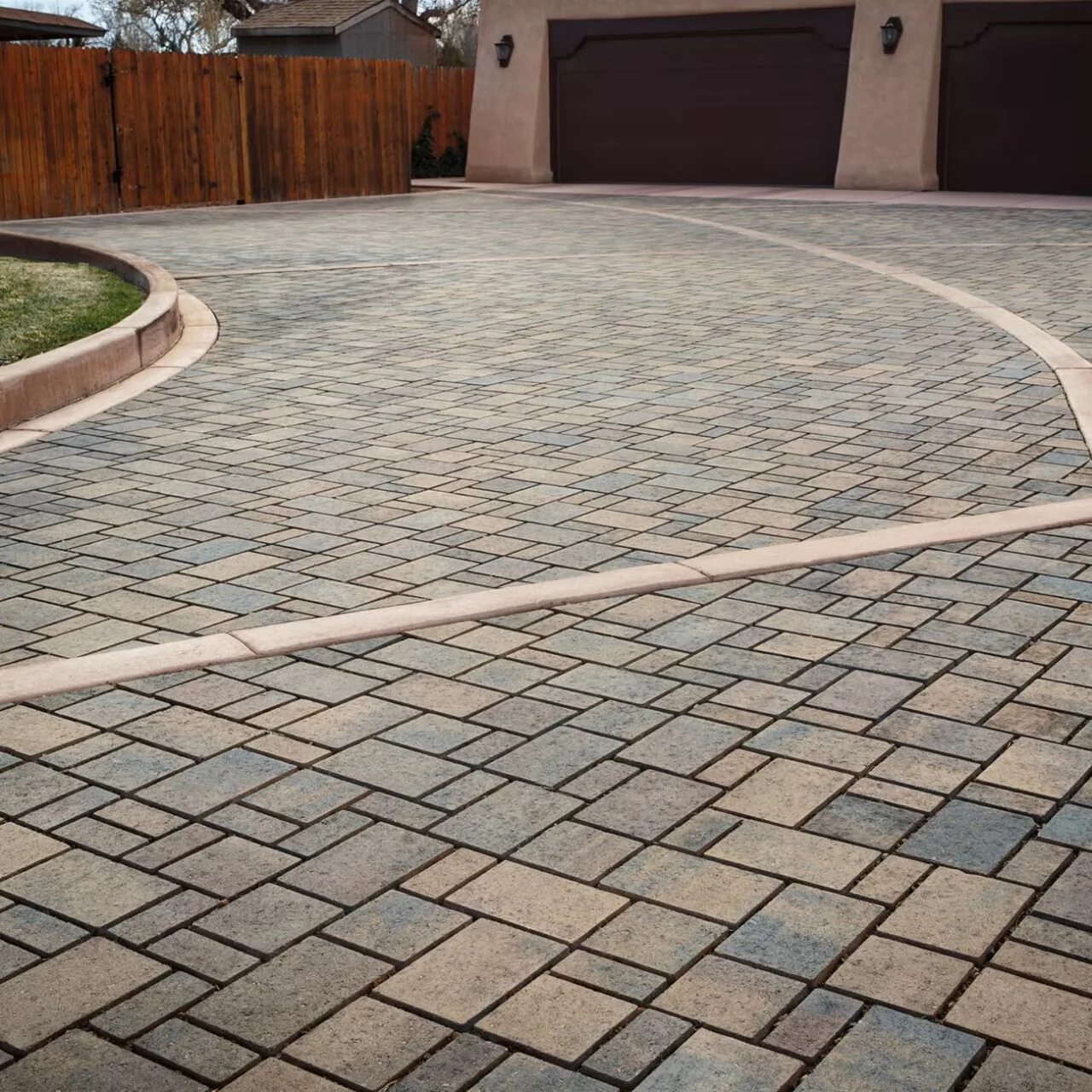 Borders that define the layout Gray paver driveway with contrasting curved borders and cross bands.