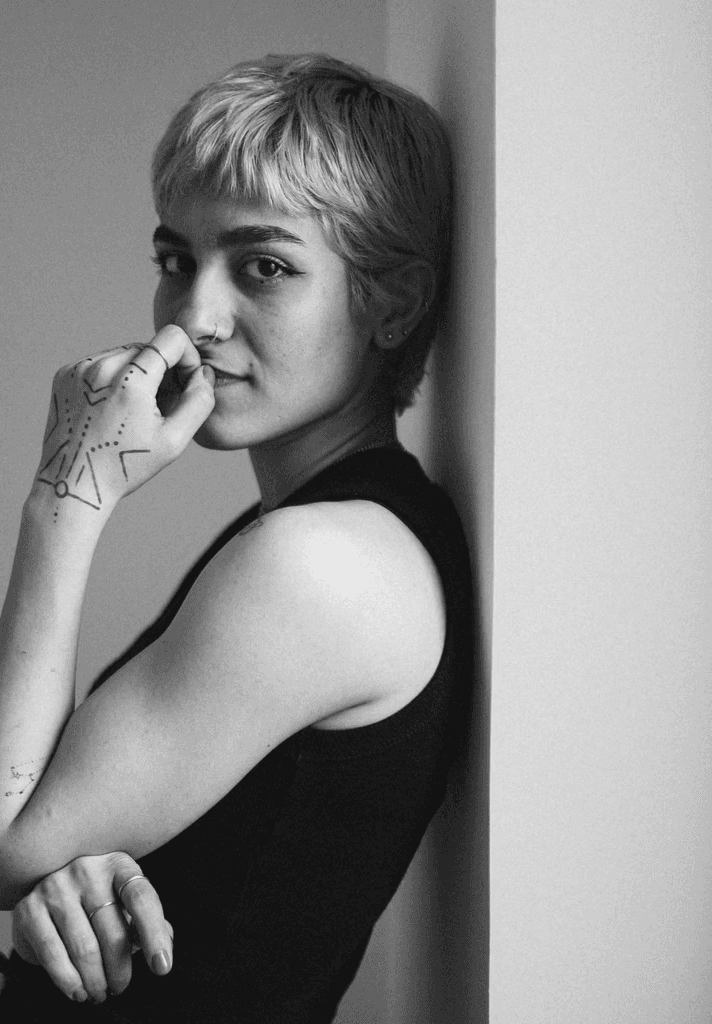 A woman leans against a wall and poses.