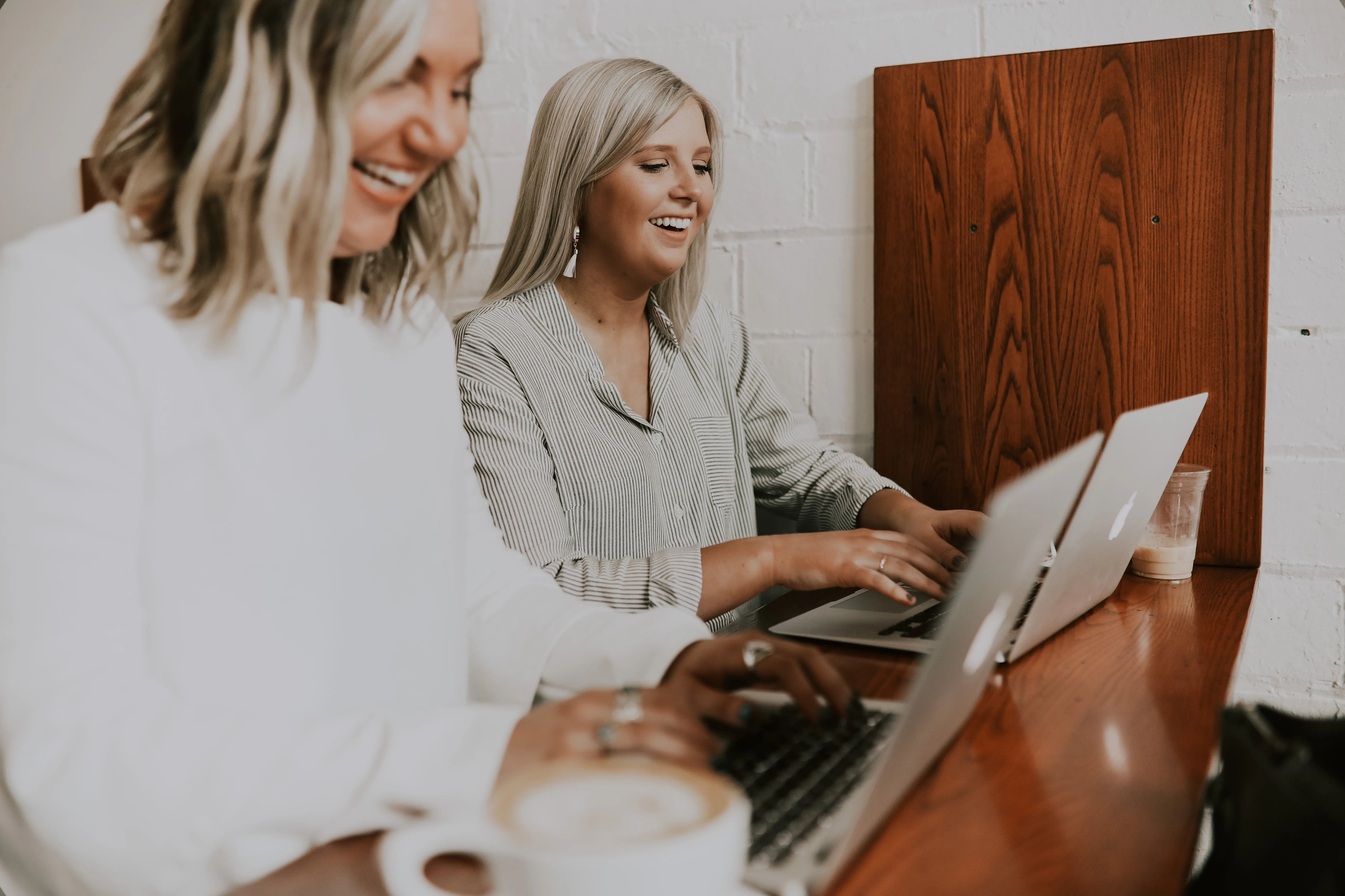 Two blonde women using their MacBook Air laptops