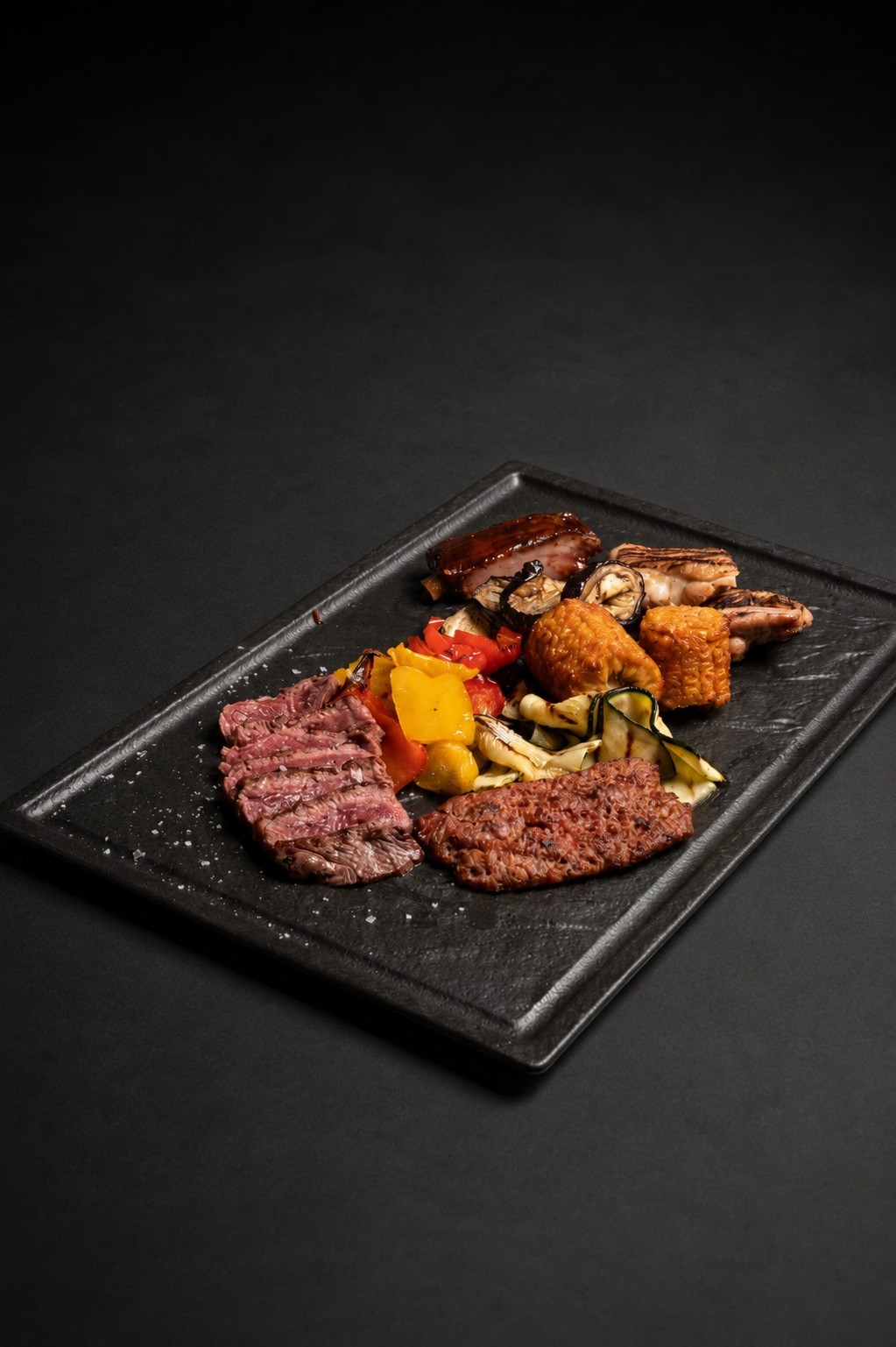 Mix con sovracoscia di pollo, salamina, tagliata di manzo, costina in salsa BBQ e verdure grigliate su vassoio in ardesia nero