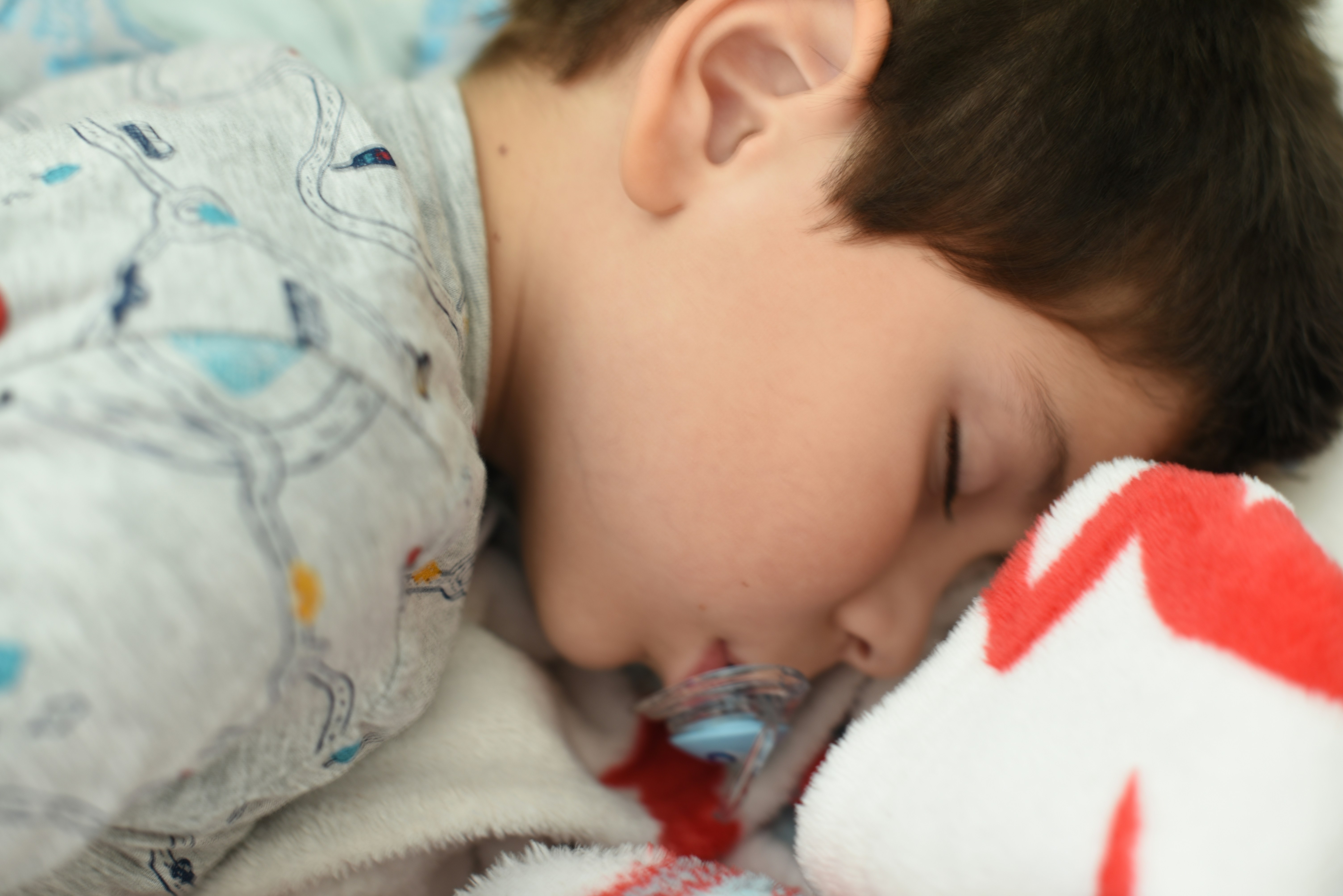 a young boy sleeping on a bed with a stuffed animal