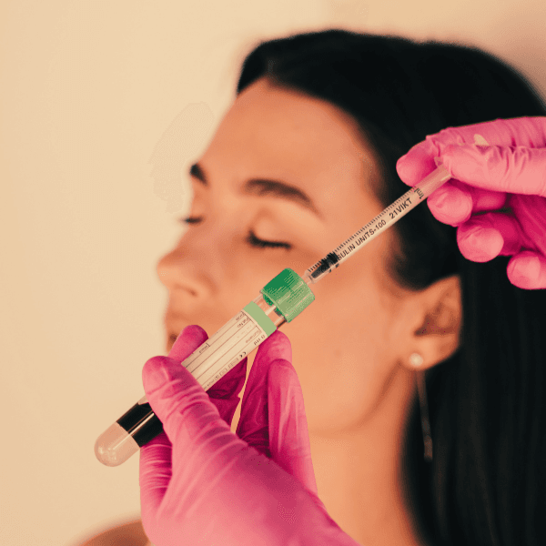 Woman in backgroud awaiting PRP for Pain treatment by physician preparing needle for injection