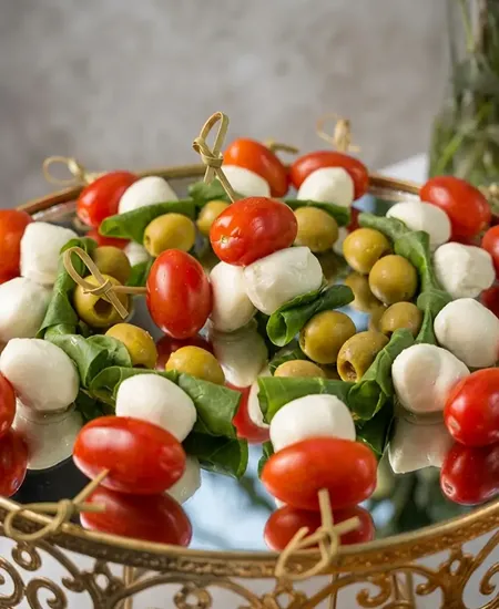 Brochetas caprese con aceitunas en base dorada para cóctel de matrimonios y banquetes en Santiago.
