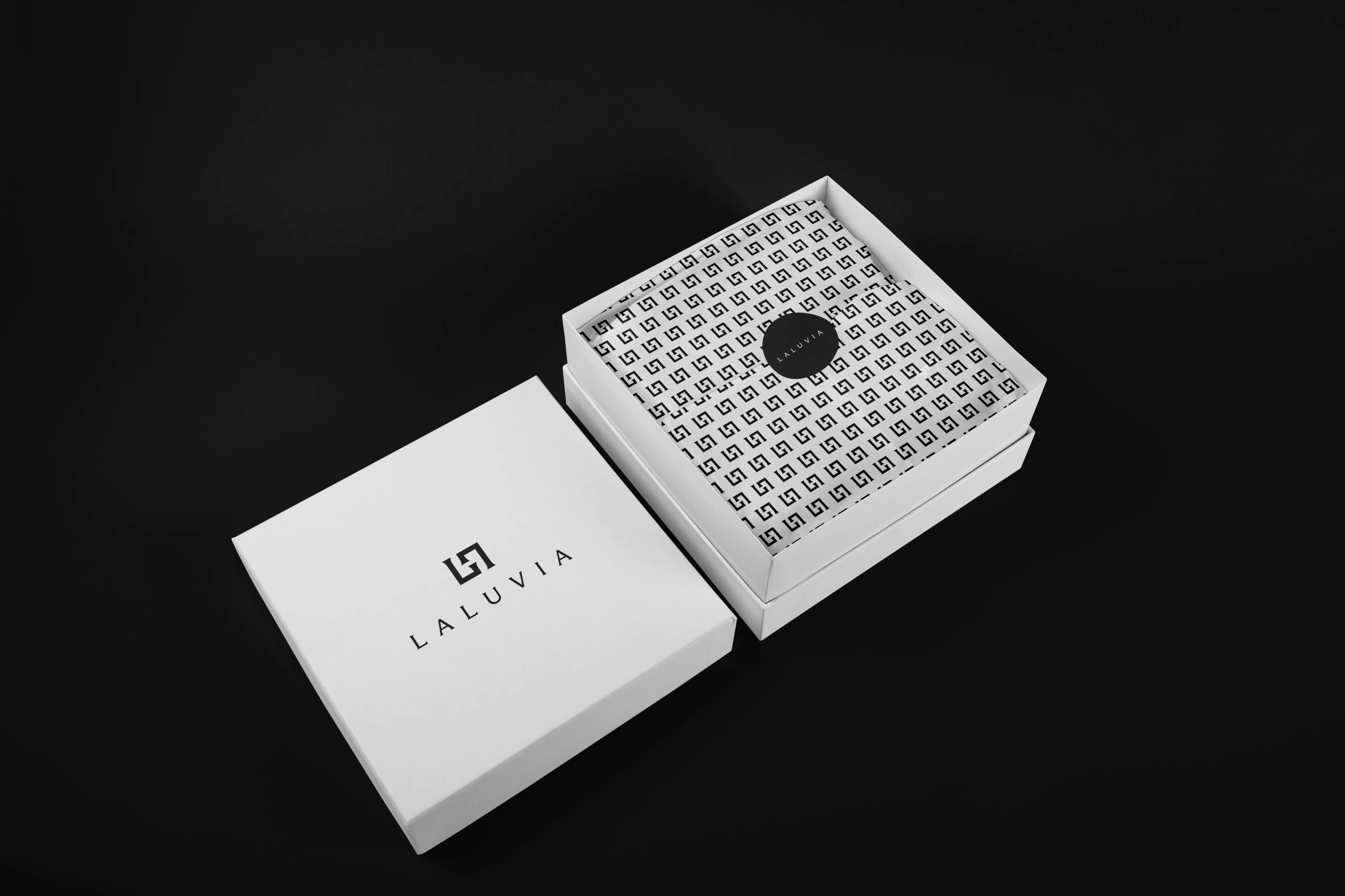 Open luxury packaging for Laluvia including a white square box and a matching monogrammed brand material.