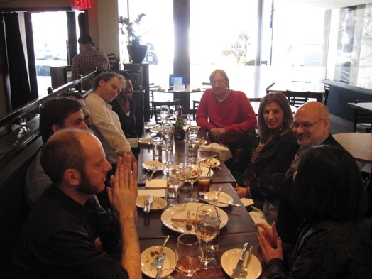 A photo of a group of people sitting next to each other at a restaurant table.