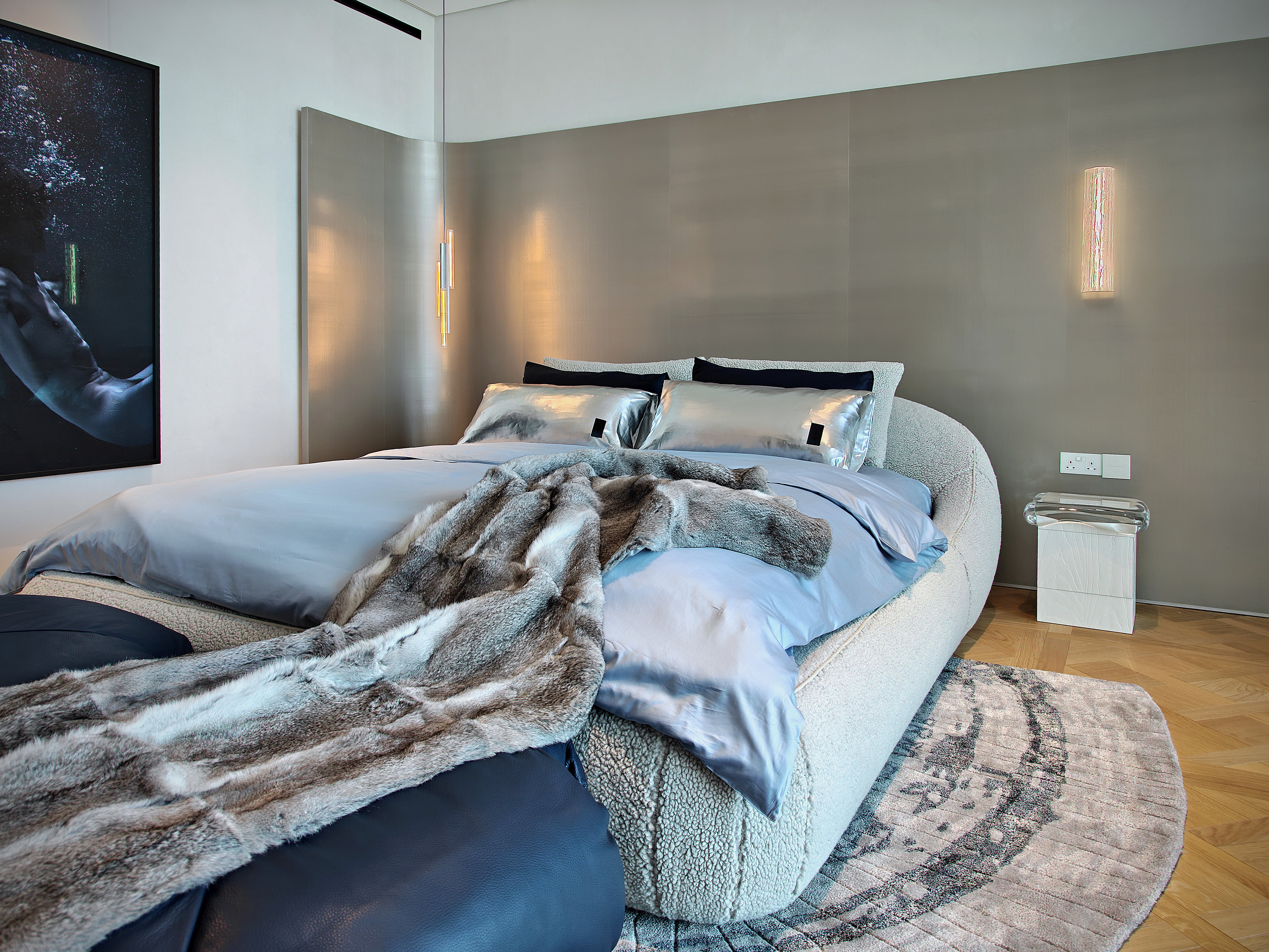 A softly lit hallway with a series of arched doorways, warm-toned walls, and wood flooring leading toward a seating area with neutral furniture.