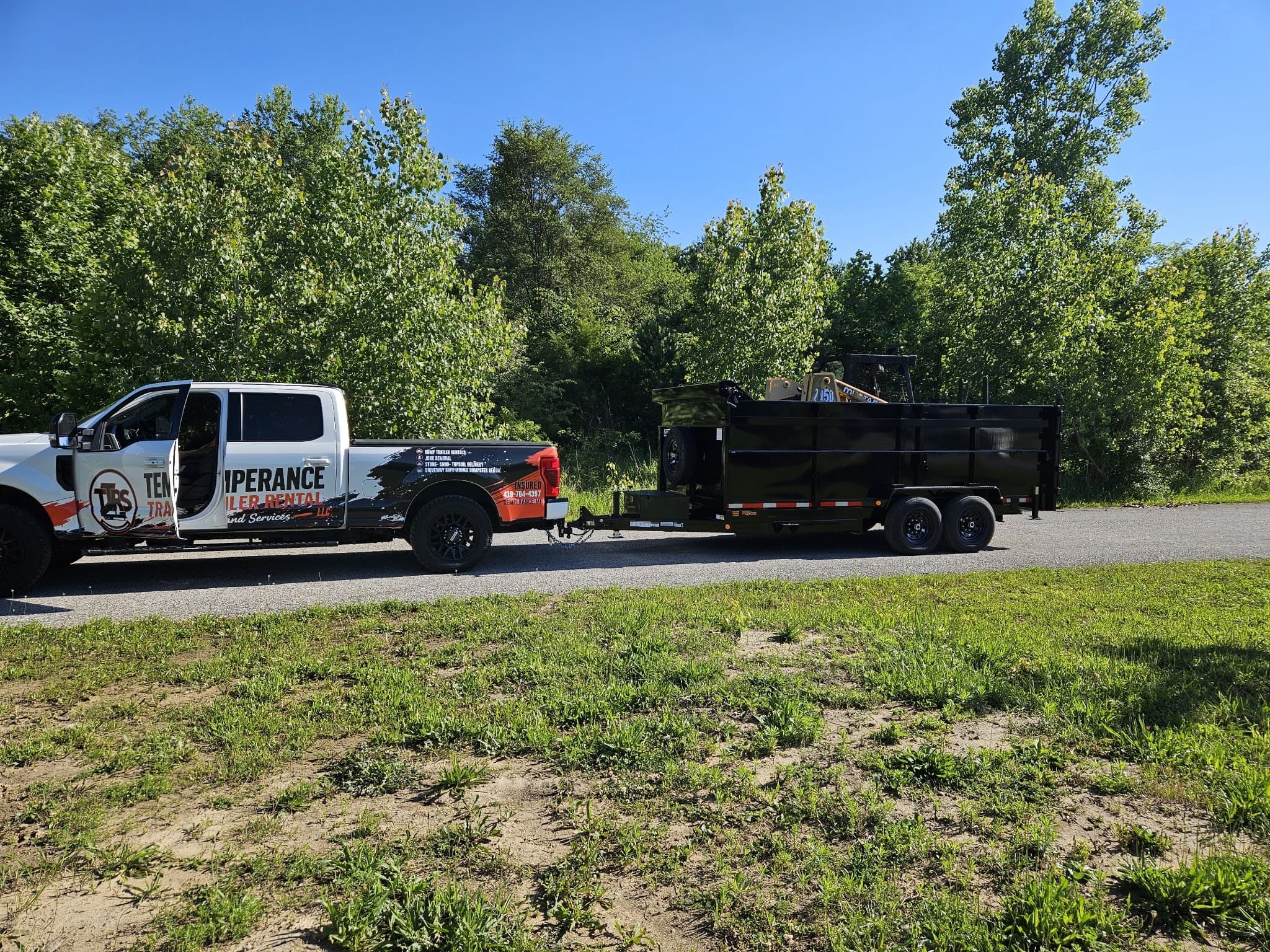 Temperance Trailer Rentals truck towing a loaded black dumpster trailer for junk removal