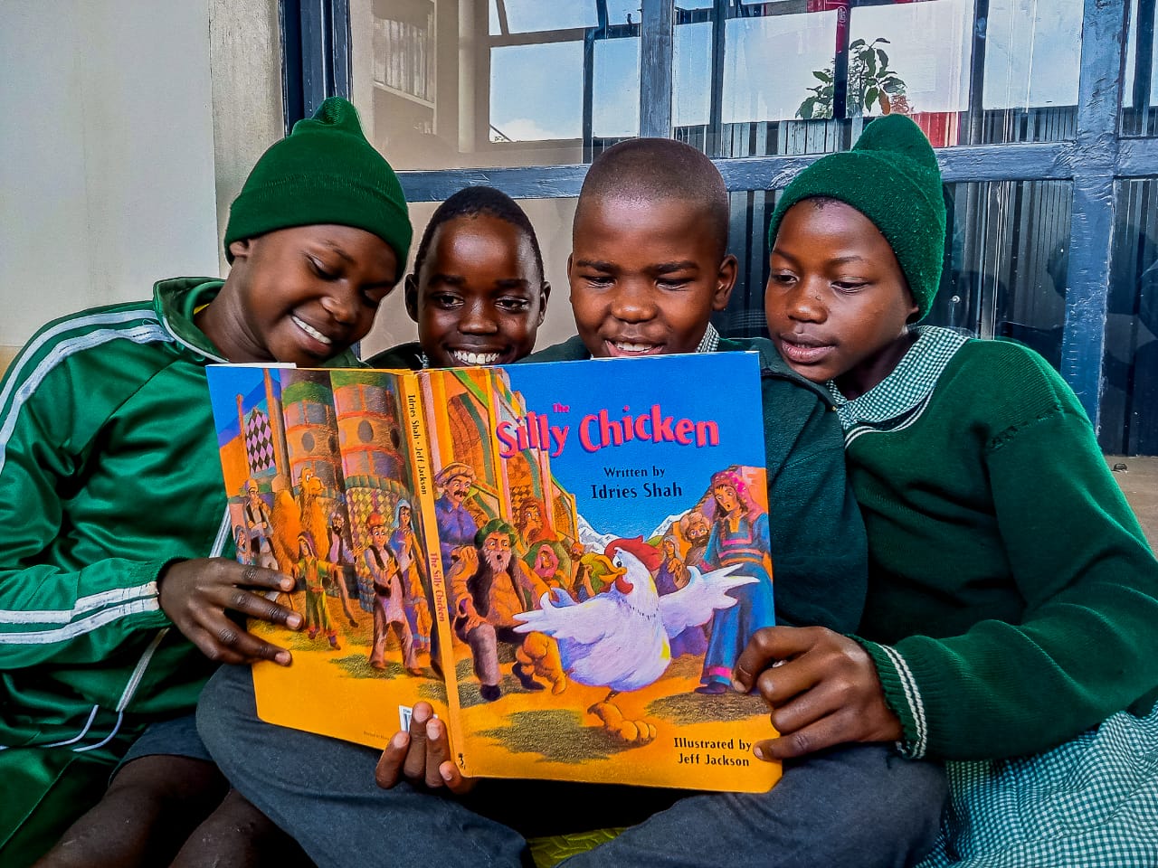 Schoolchildren in green uniforms reading a Hoopoe book