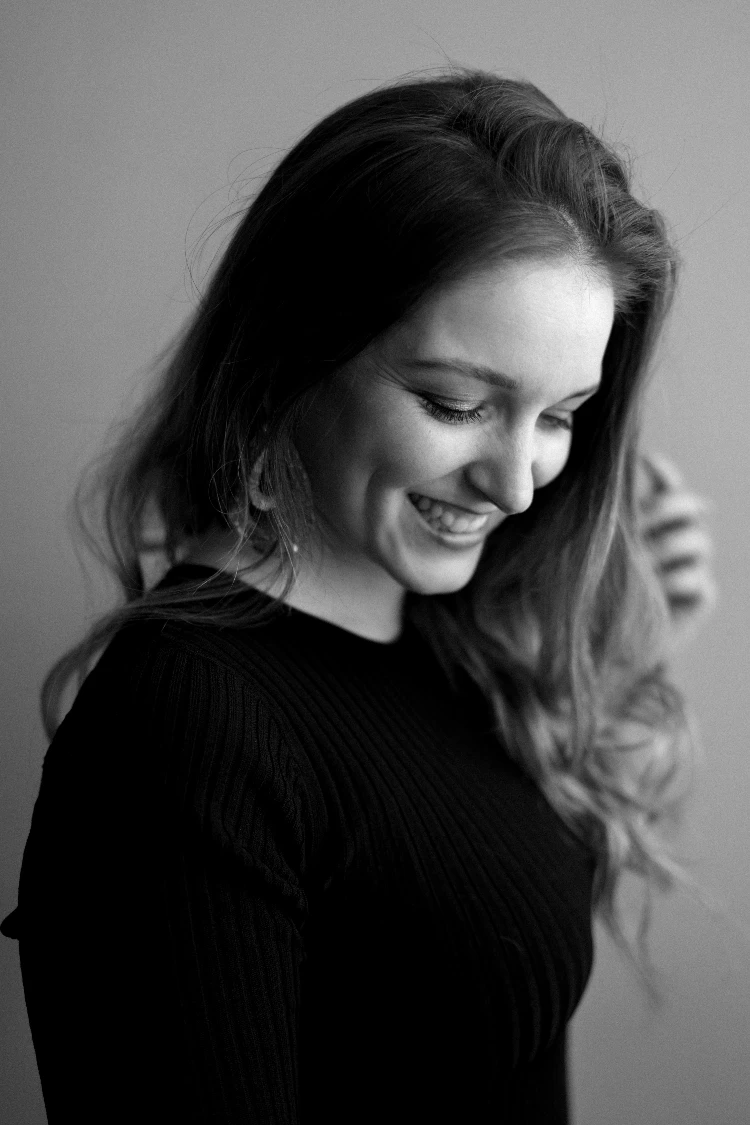 Smiling woman in black, captured by Ramona in a Sensual Boudoir photography session.