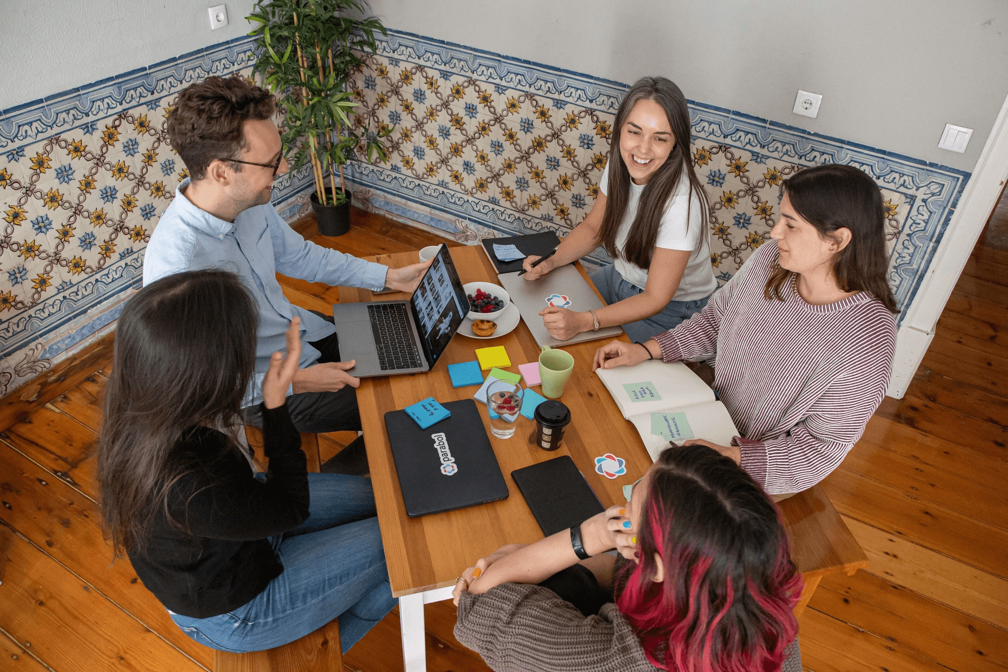 Three kids are sitting around a table with laptops and snacks nearby.