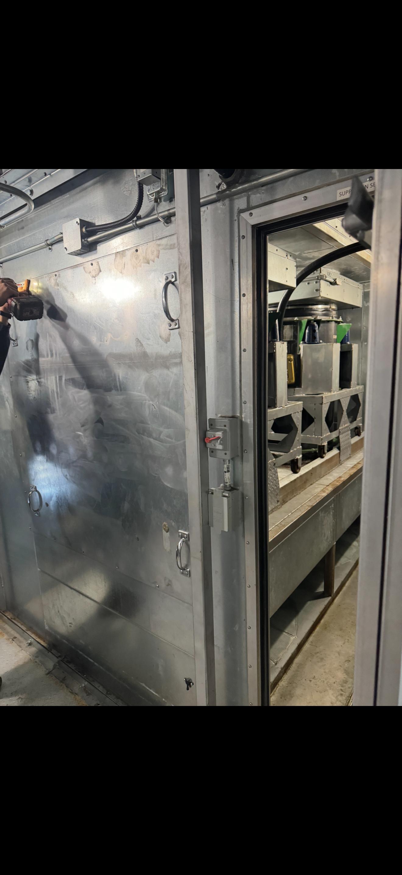 Legacy fan section inside a hospital air handling unit prior to modernization, with access panels opened for retrofit work.
