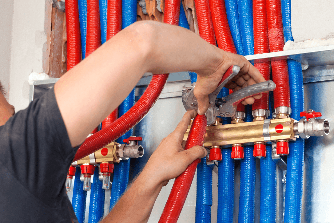 A smiling young man with crossed arms, wearing a plaid shirt and white t-shirt, poses against a dark background.