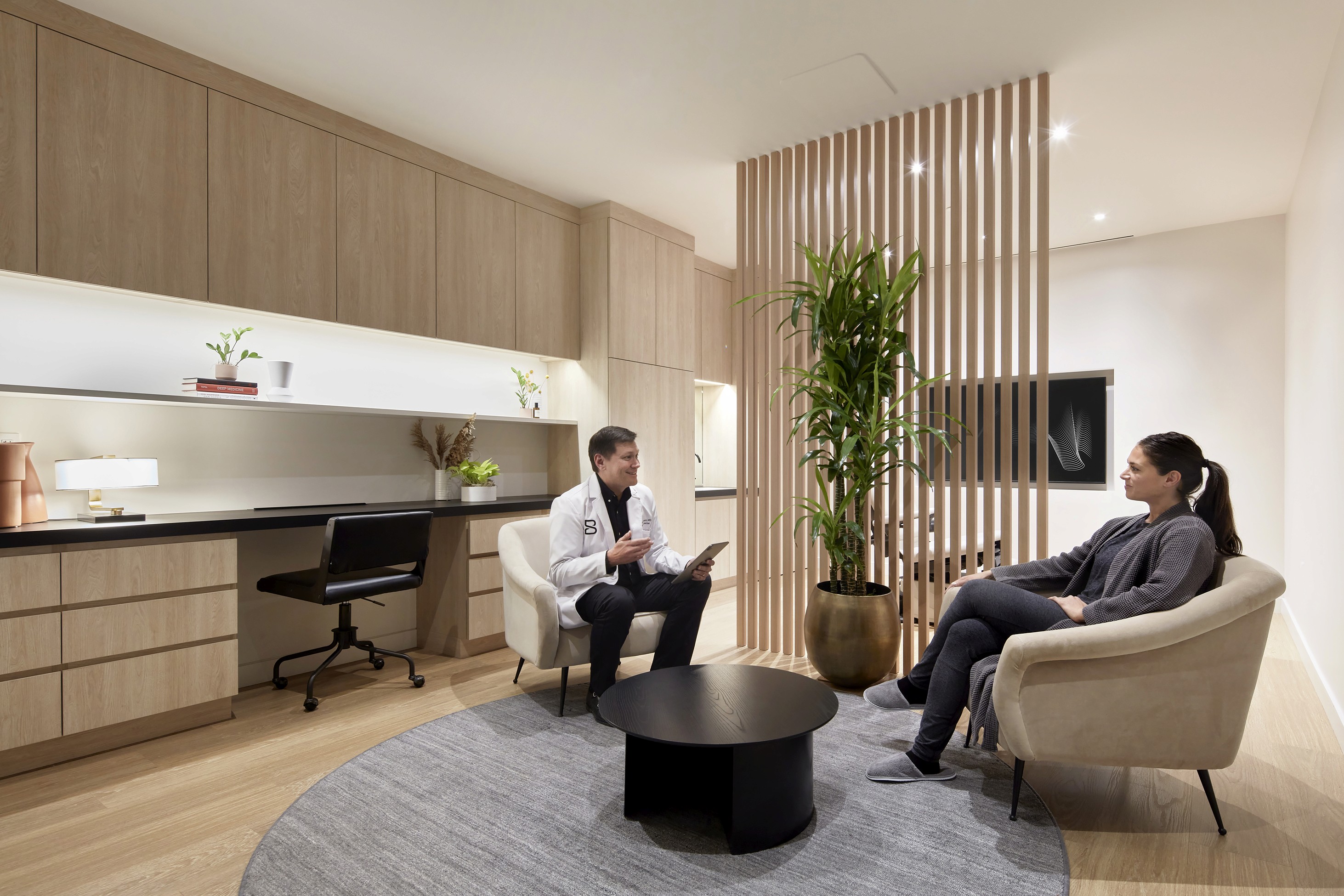 Biograph physician consulting with a patient in a calm, modern exam room.