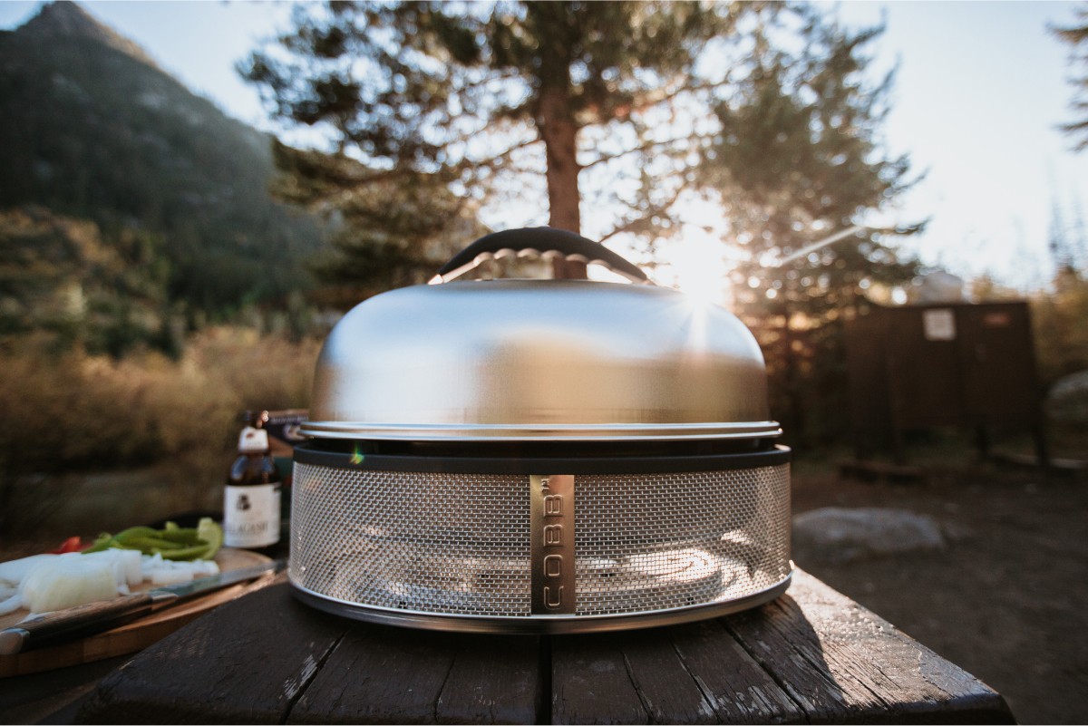 Parrilla COBB Supreme sobre una mesa en la montaña