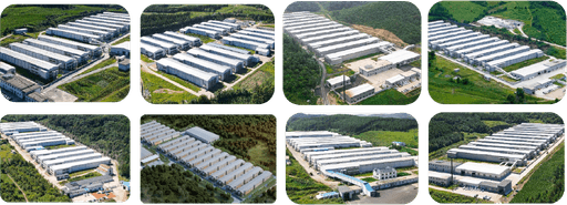 Aerial view of a vast industrial park featuring multiple large, rectangular white warehouses surrounded by lush greenery and well-maintained roads.