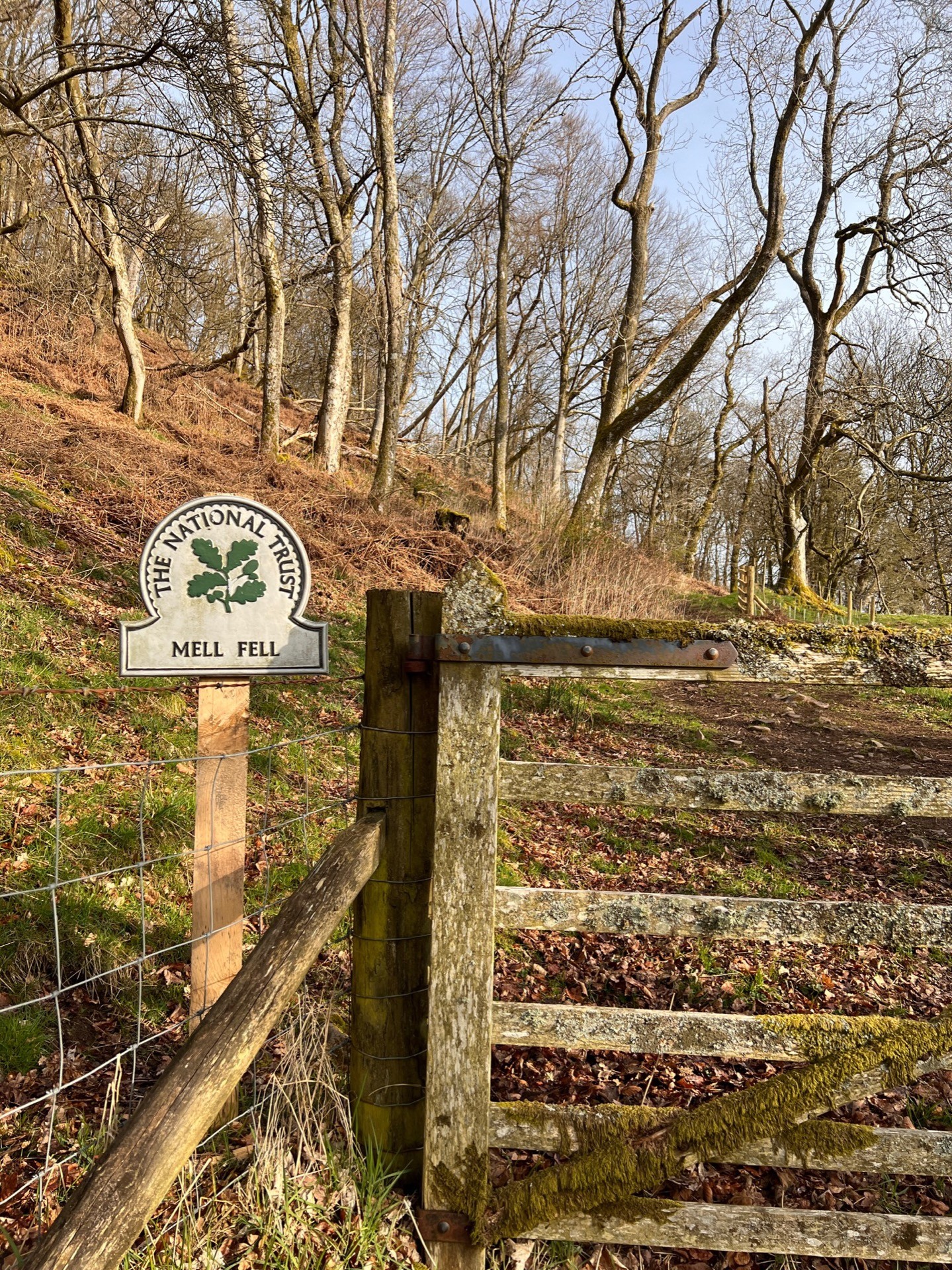 A sign next to a wooden gate that reads "The National Trust, Mell Fell".