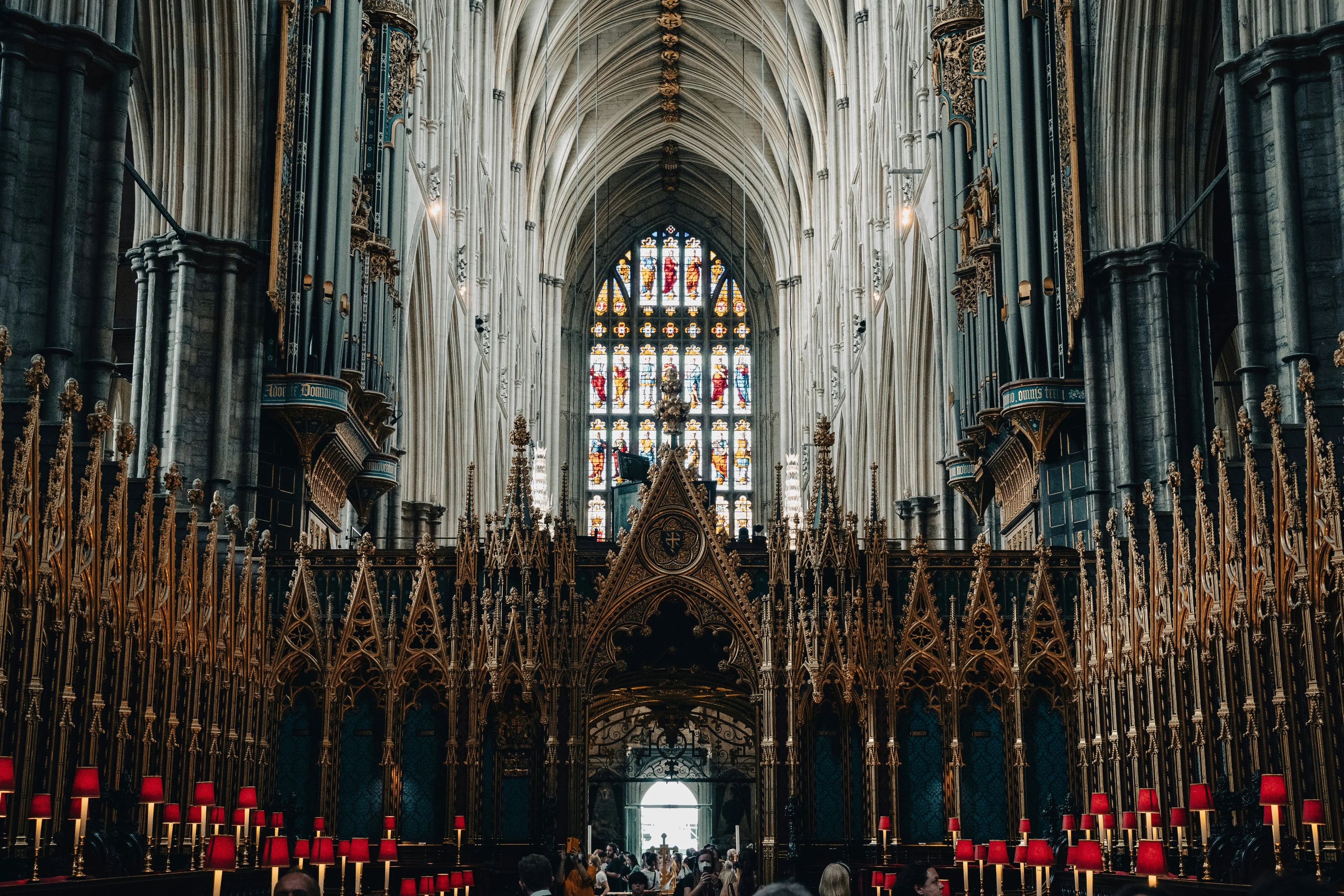 A colorful and ornate stained glass panel with light shining through within the Westminster Abbey in London.