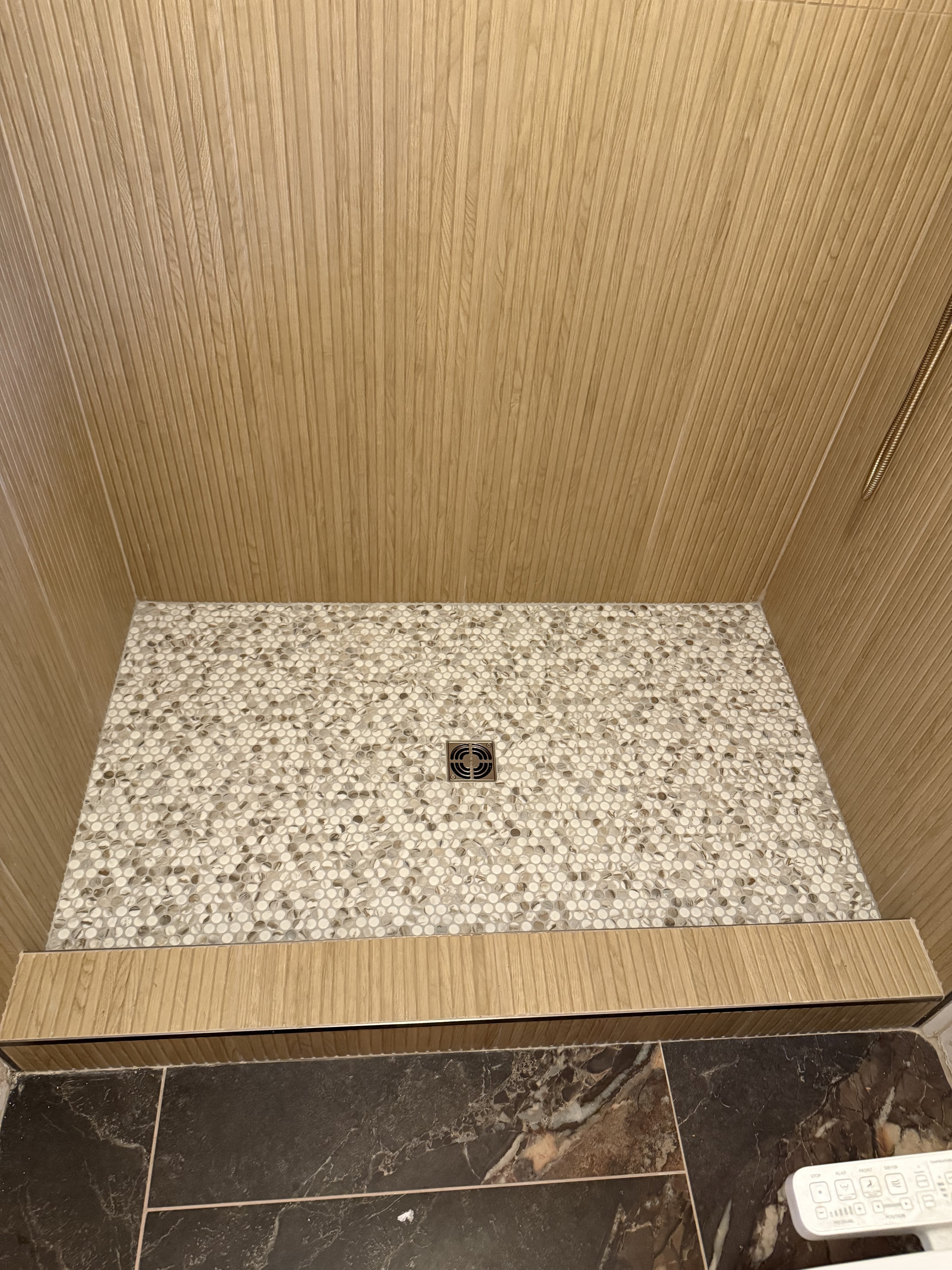Bathtub shower combo with sleek grey marble-look large format wall tiles, a built-in shower niche with a white and grey hexagonal mosaic tile accent, and modern chrome fixtures.
