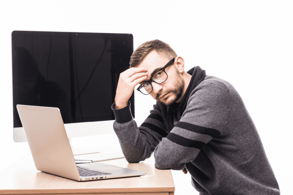 Homem com expressão cansada diante do computador, representando dificuldades com suporte de TI - FindUP soluções para problemas comuns de TI