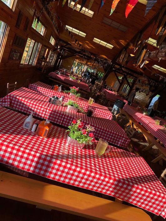 Dining hall with red checkered tablecloths and colorful pennant flags at Camp Lenox