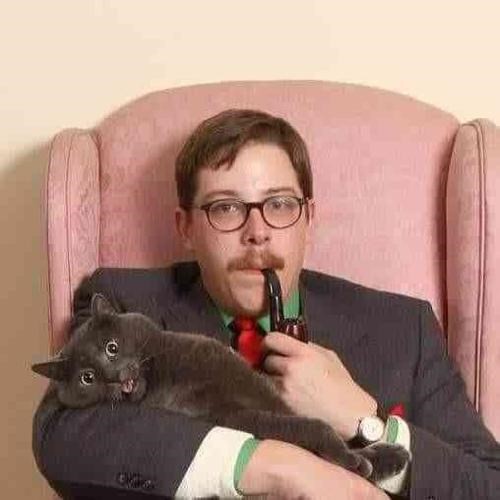 Portrait of a young man in a suit and glasses holding a cat in one hand and a pipe in the other