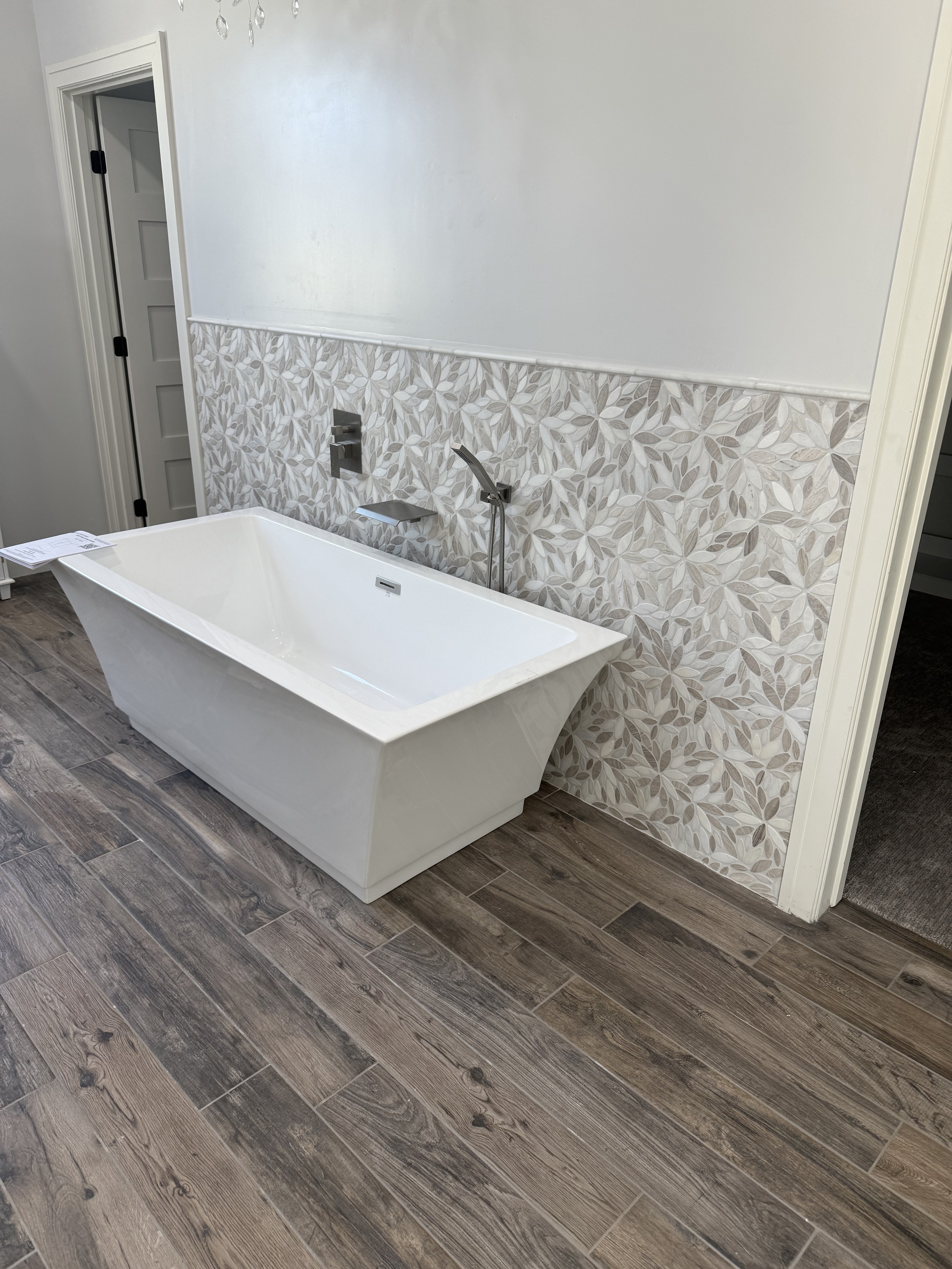 Contemporary kitchen with dark cabinets, a white herringbone tile backsplash, and a sink on a white countertop.