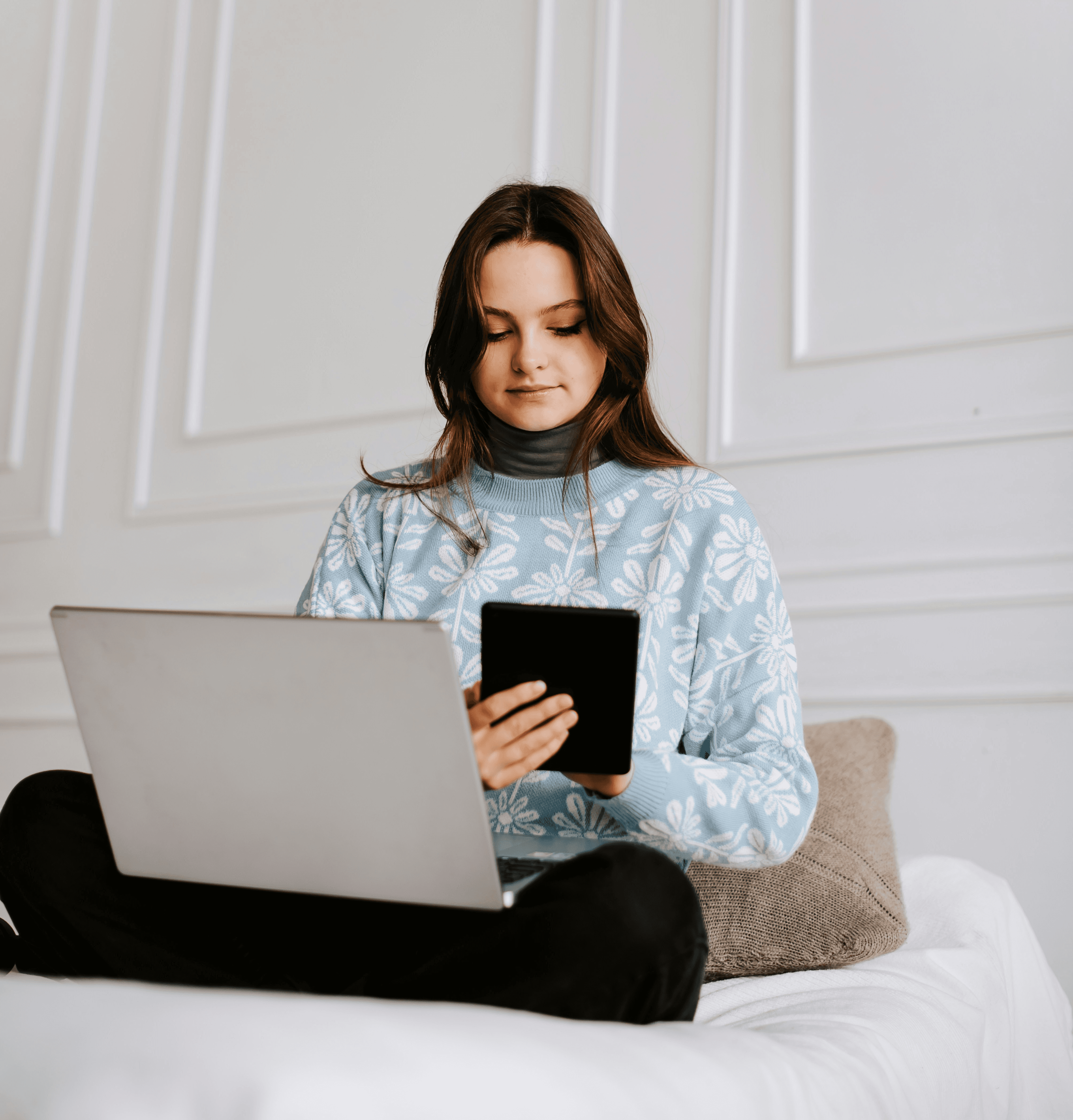 a woman sitting on a bed looking at a tablet