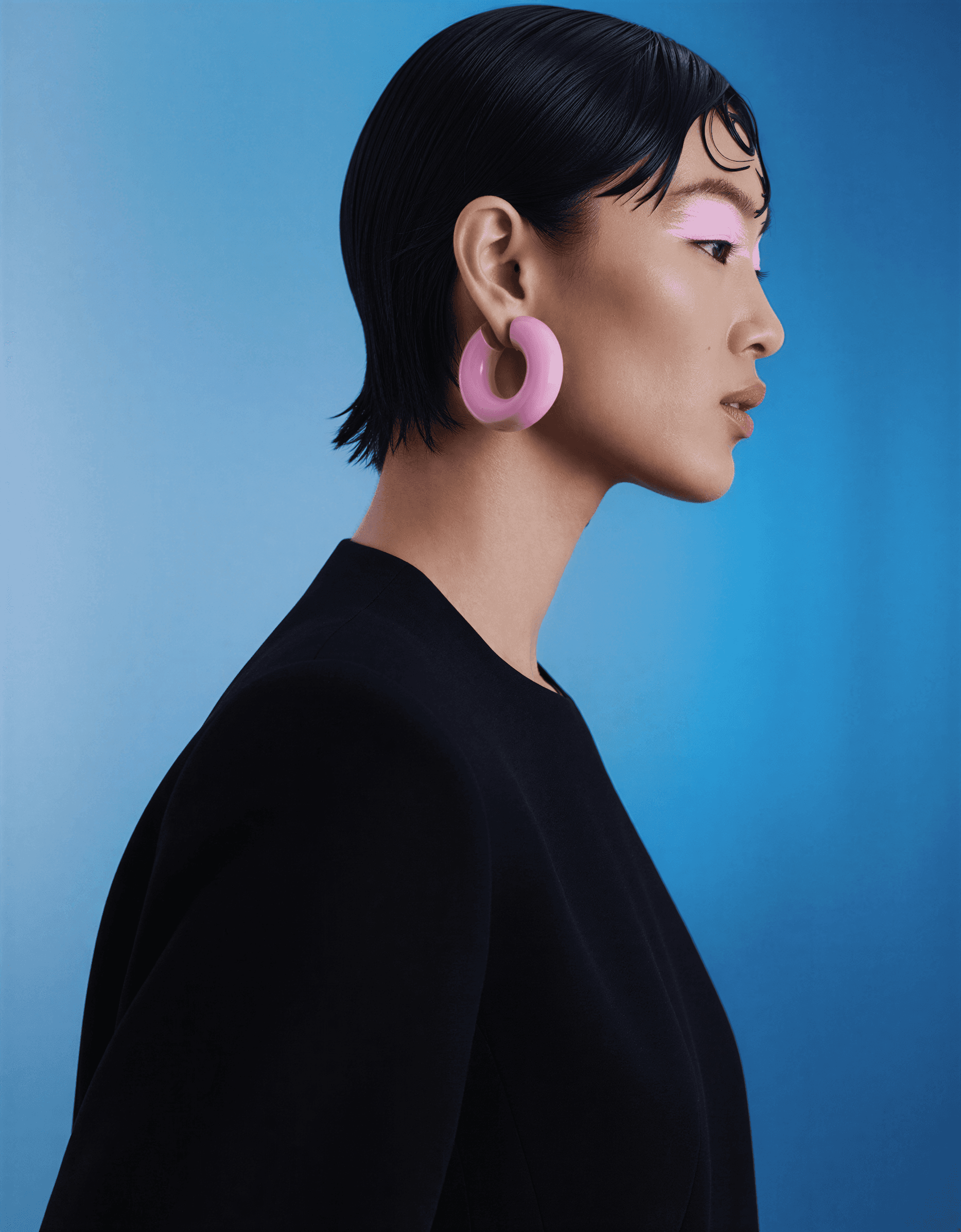 Woman with pink eye makeup and a large hoop earring.