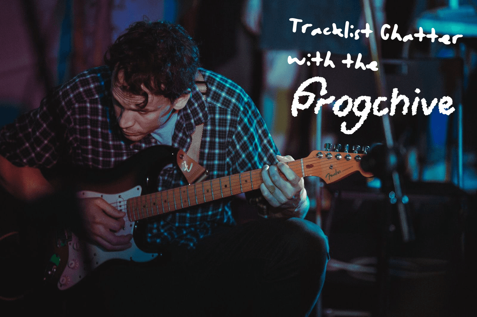 Daniel Bateman Crouched, Strumming a Guitar, with the text "Tracklist Chatter with the Frogchive"