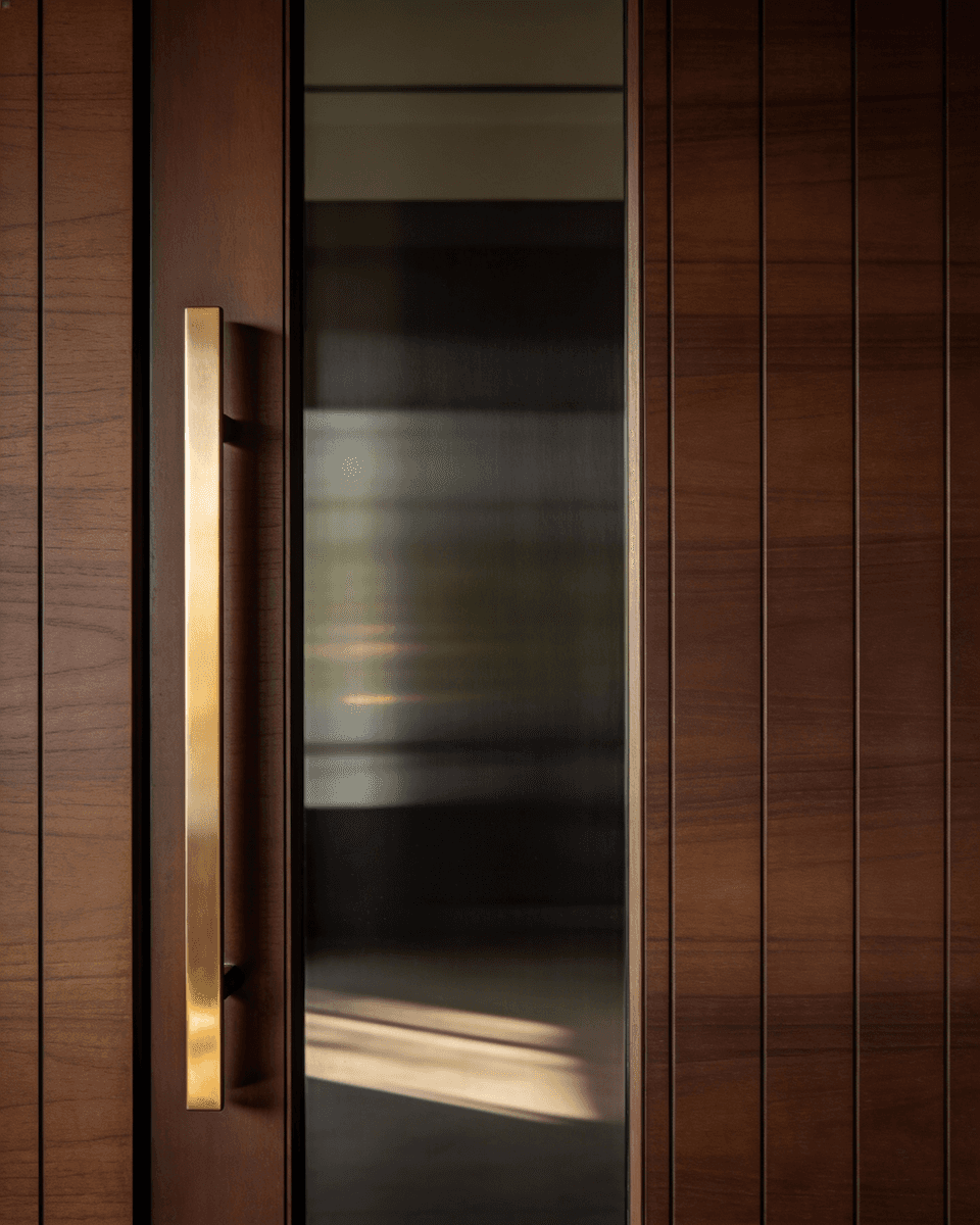 Solid oak entrance door with oversized brass handle and warm timber detailing.