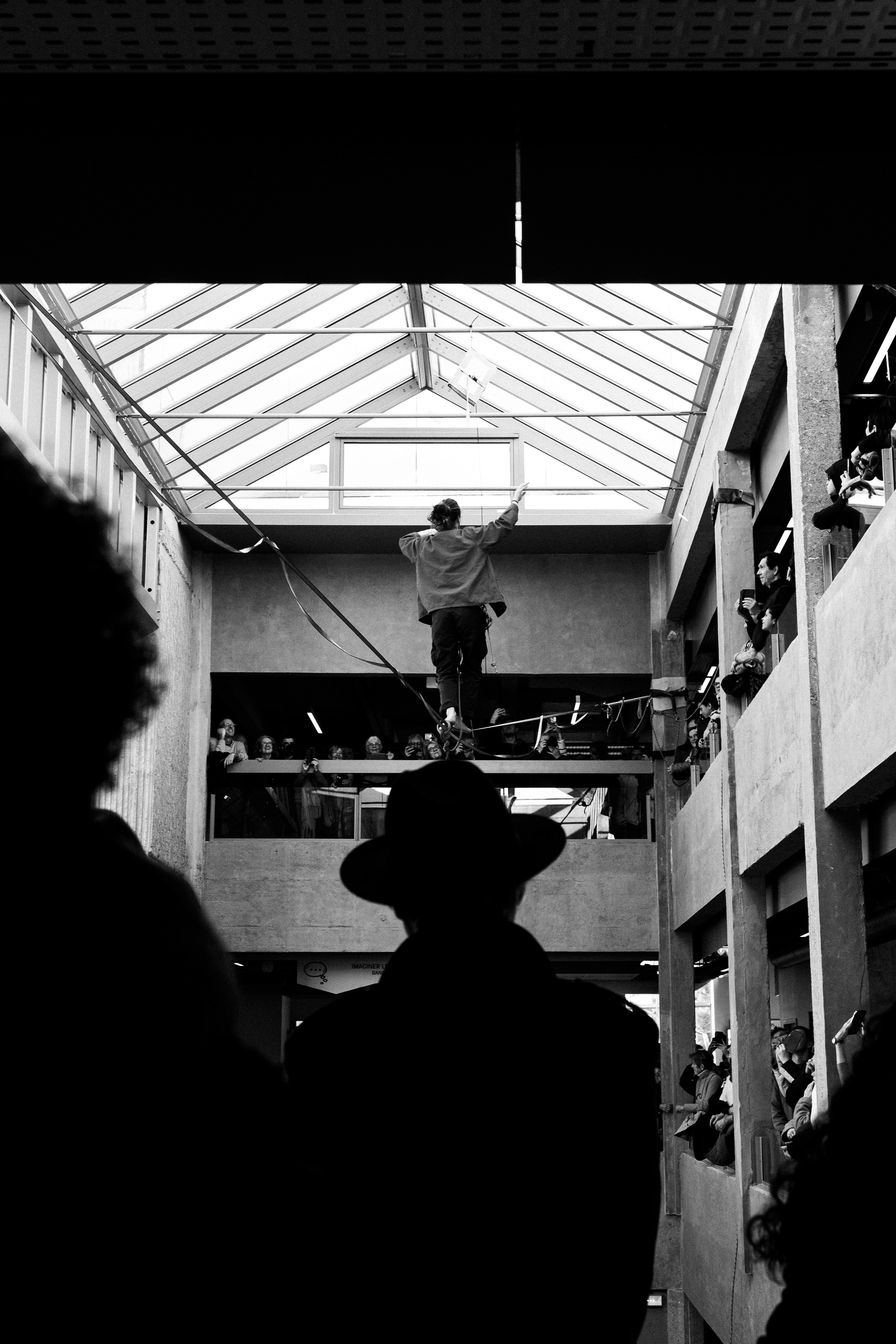 A silhouette of a person wearing a hat stands in front of a funambulist