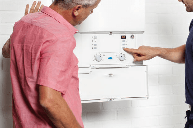 Gas engineer showing man how to use a boiler