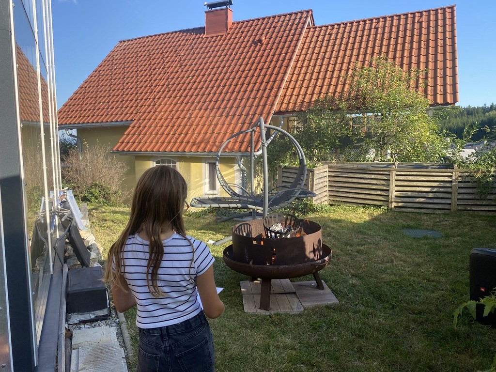 Gartenszene mit Kind und Feuerschale am Haus
